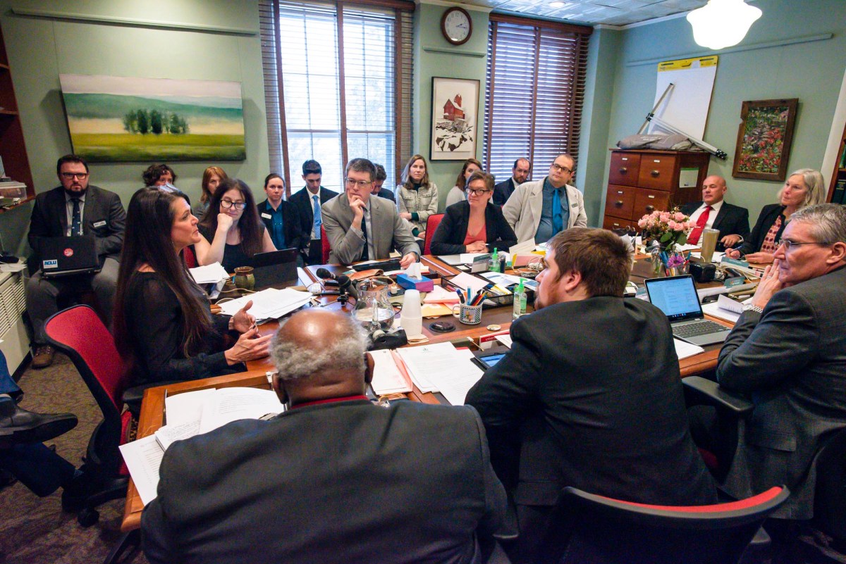 a group of people sitting around a table with laptops.