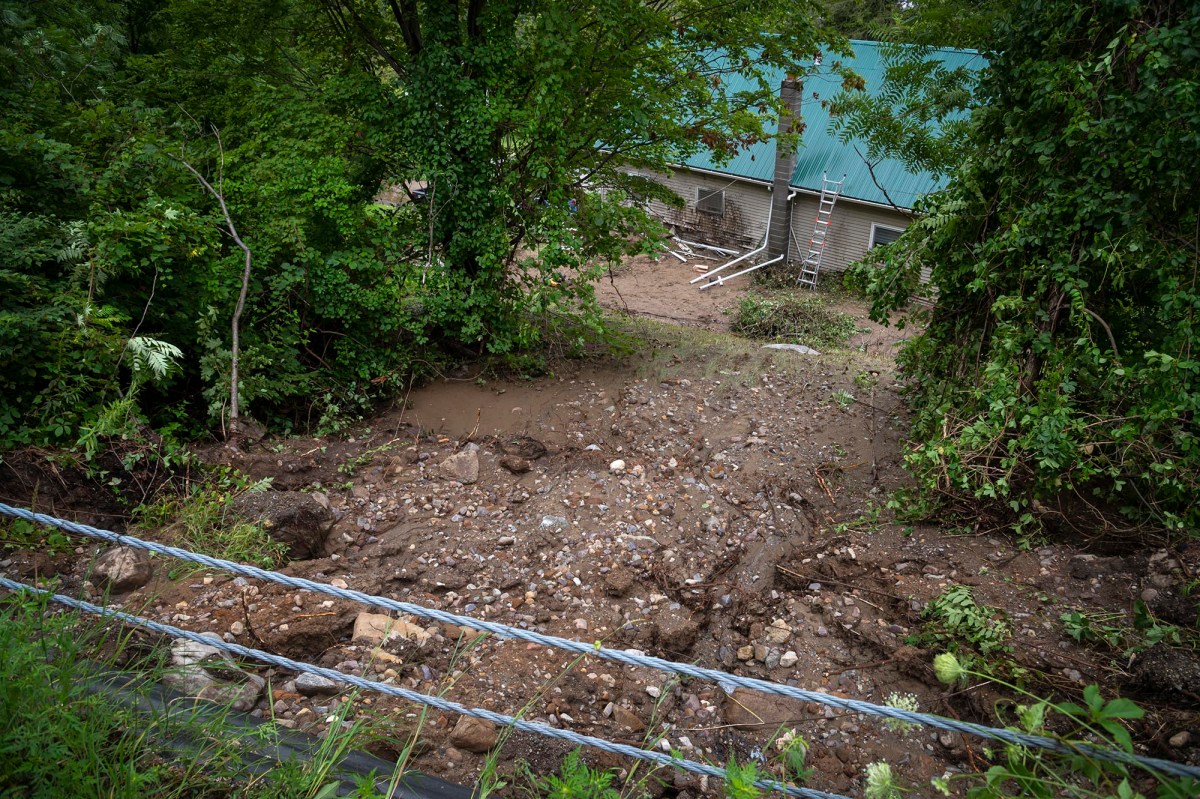A house is surrounded by mud and a fence.