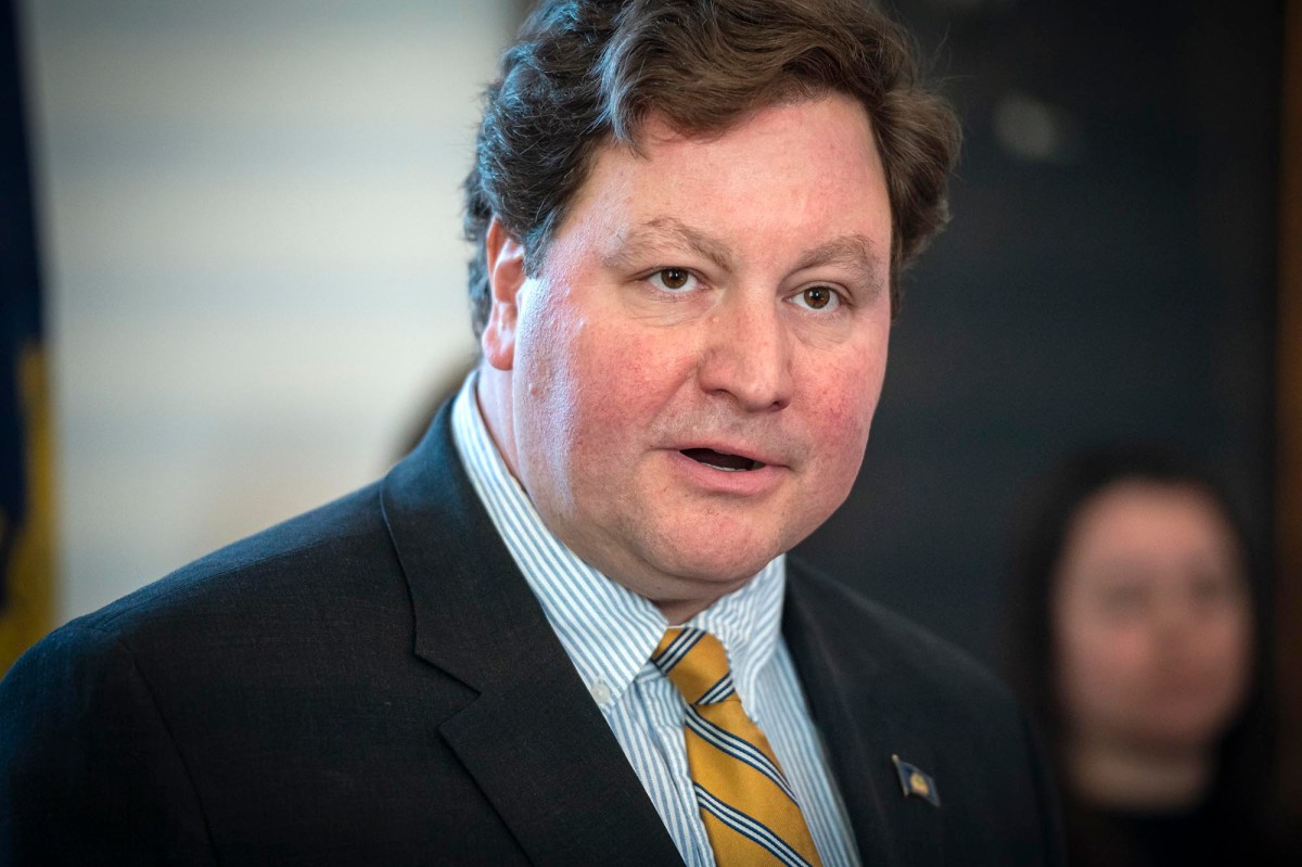 A man in a suit and tie speaking into a microphone.