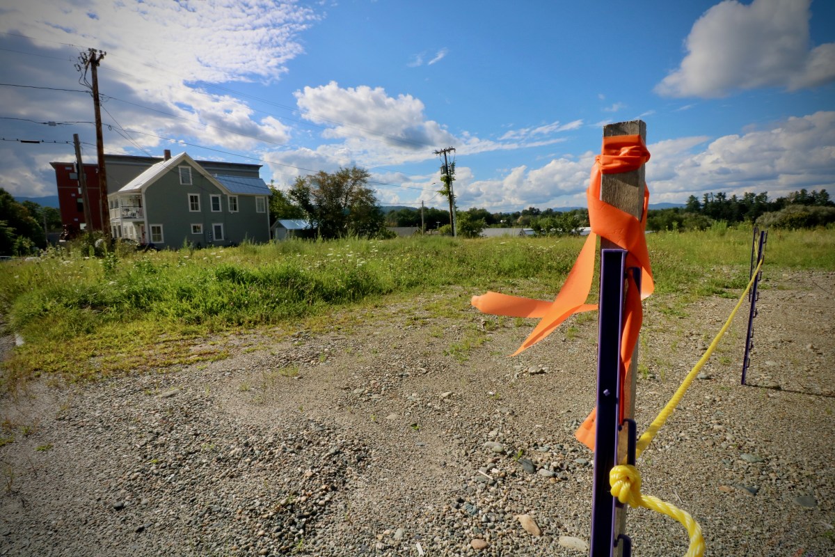 An orange ribbon is tied to a pole in front of a house.