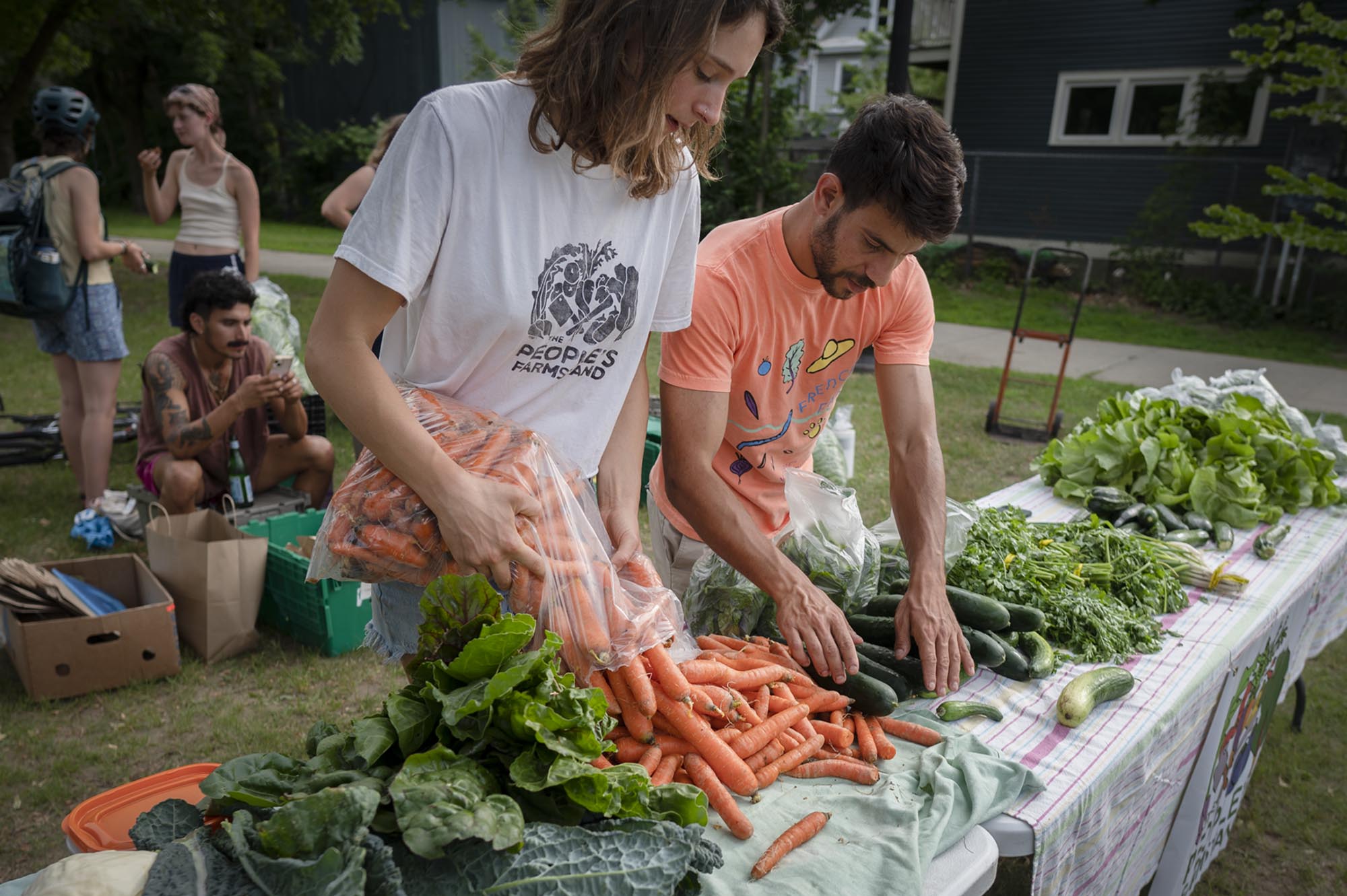 two people standing at a table full of vegetables.
