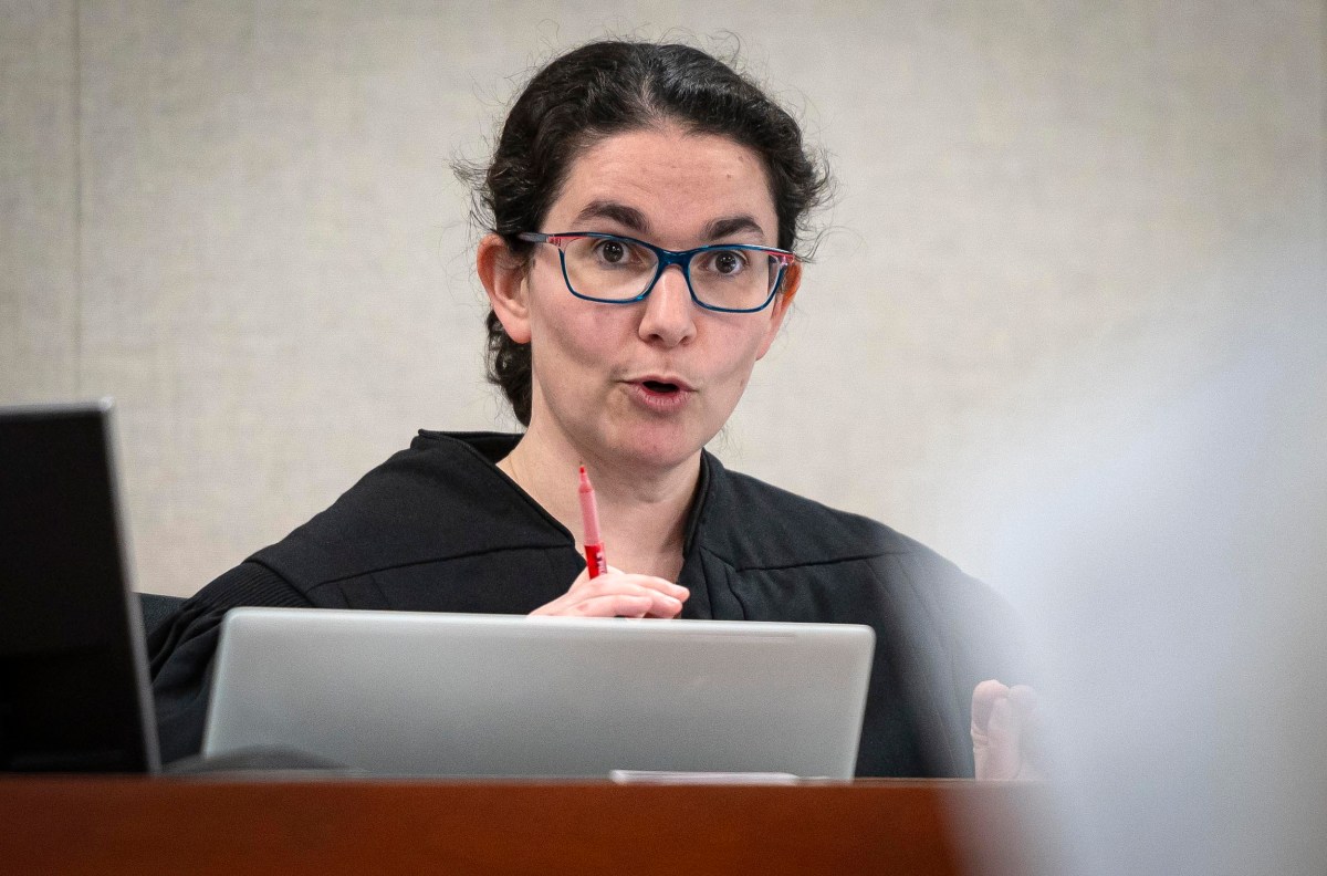 A judge gestures while speaking in a courtroom.