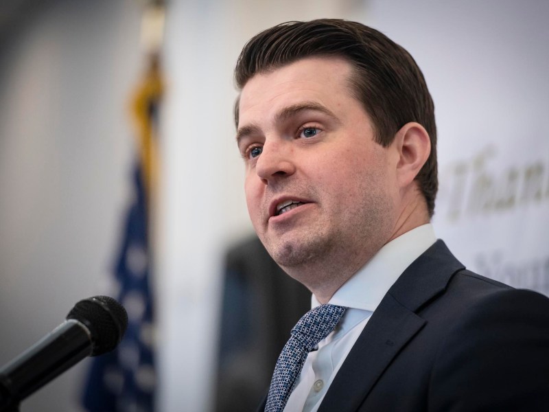 a man in a suit and tie speaks into a microphone.