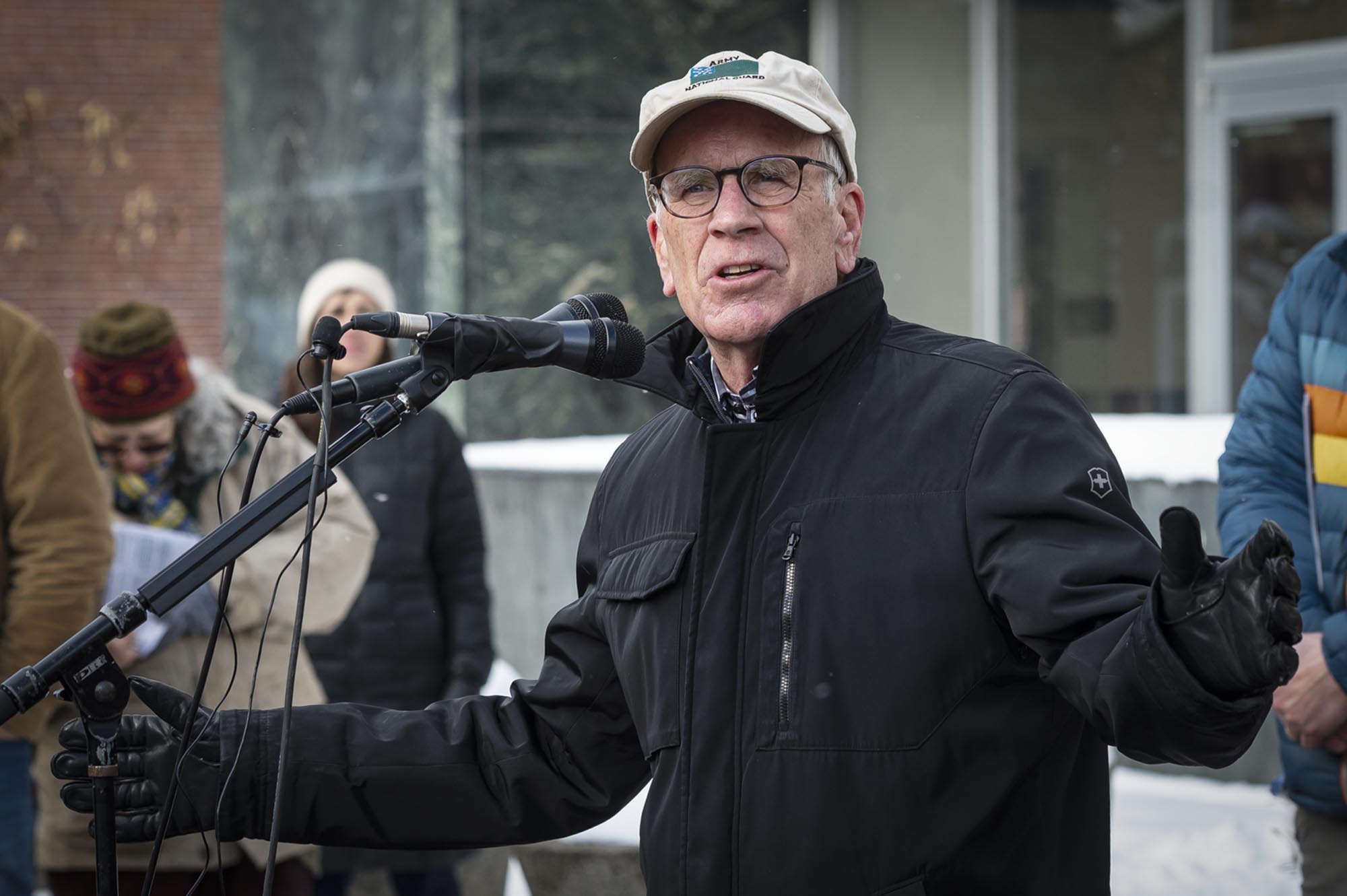 A man speaking into a microphone in front of a group of people.