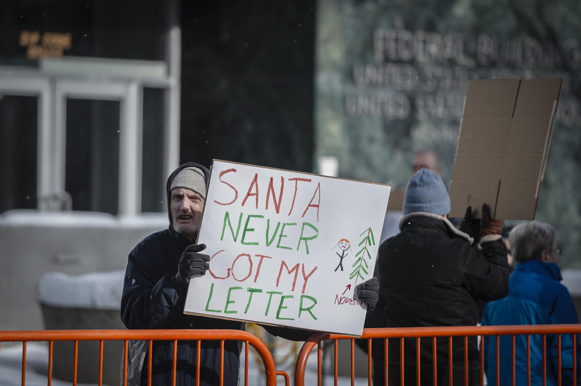 A man holding a sign that says santa never got his letter.