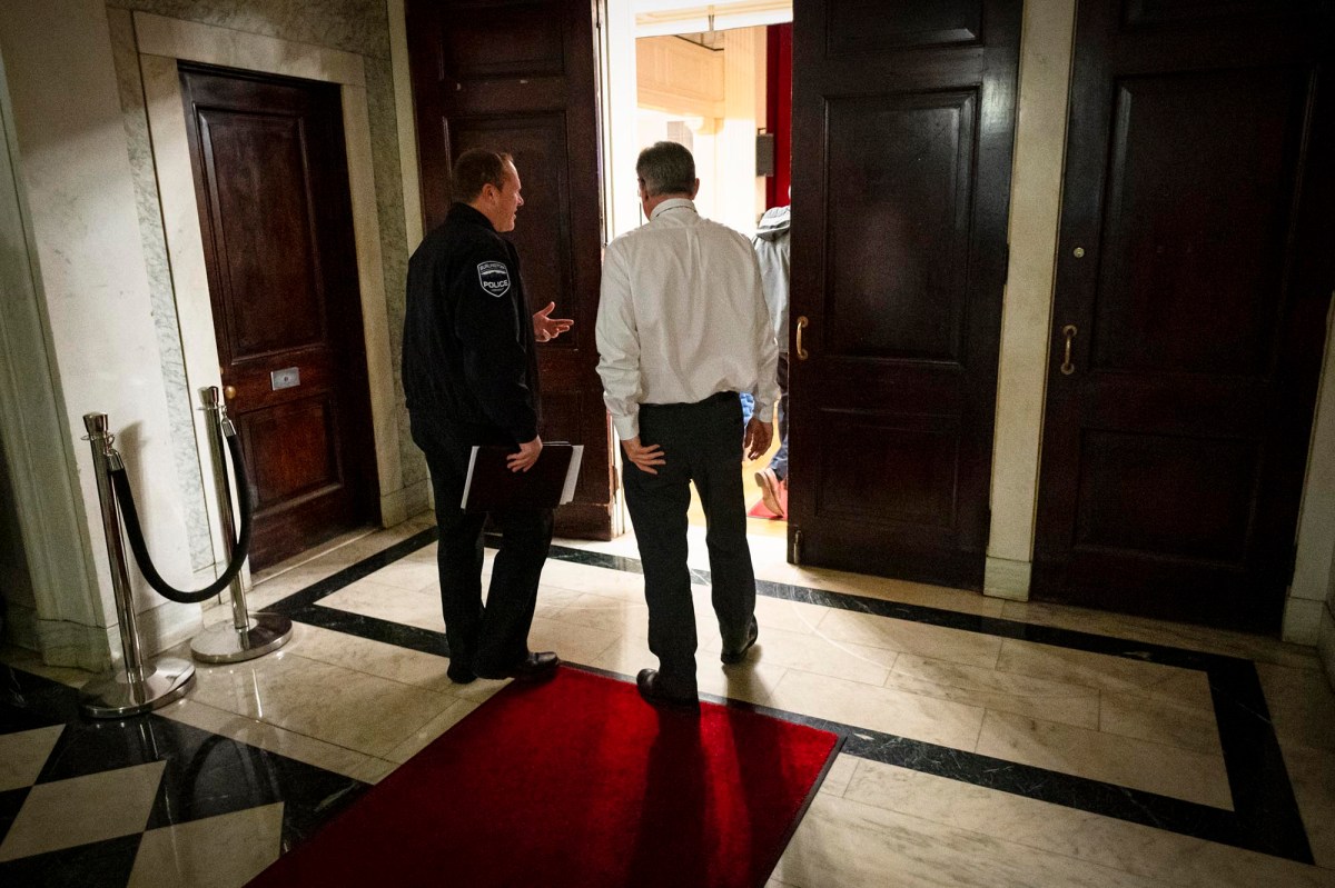Two men standing on a red carpet in a room.