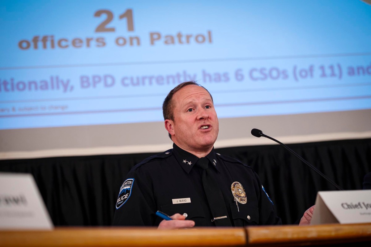 A man in a police uniform speaks at a podium.