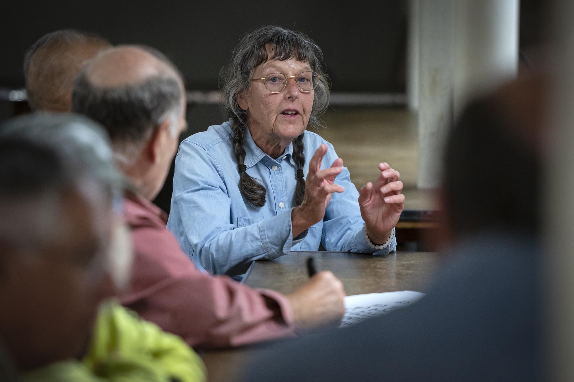 A woman sitting at a table talking to someone.