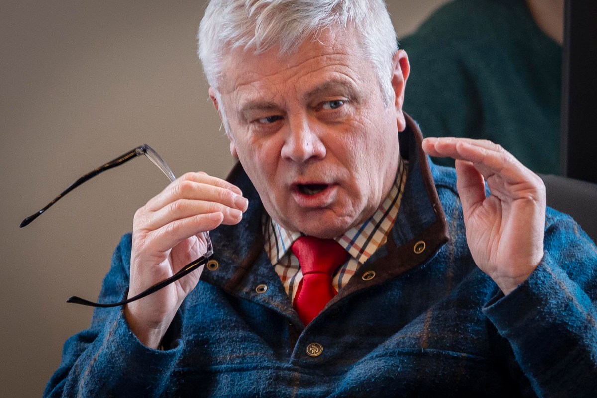 A man in a blue jacket with glasses and a red tie.