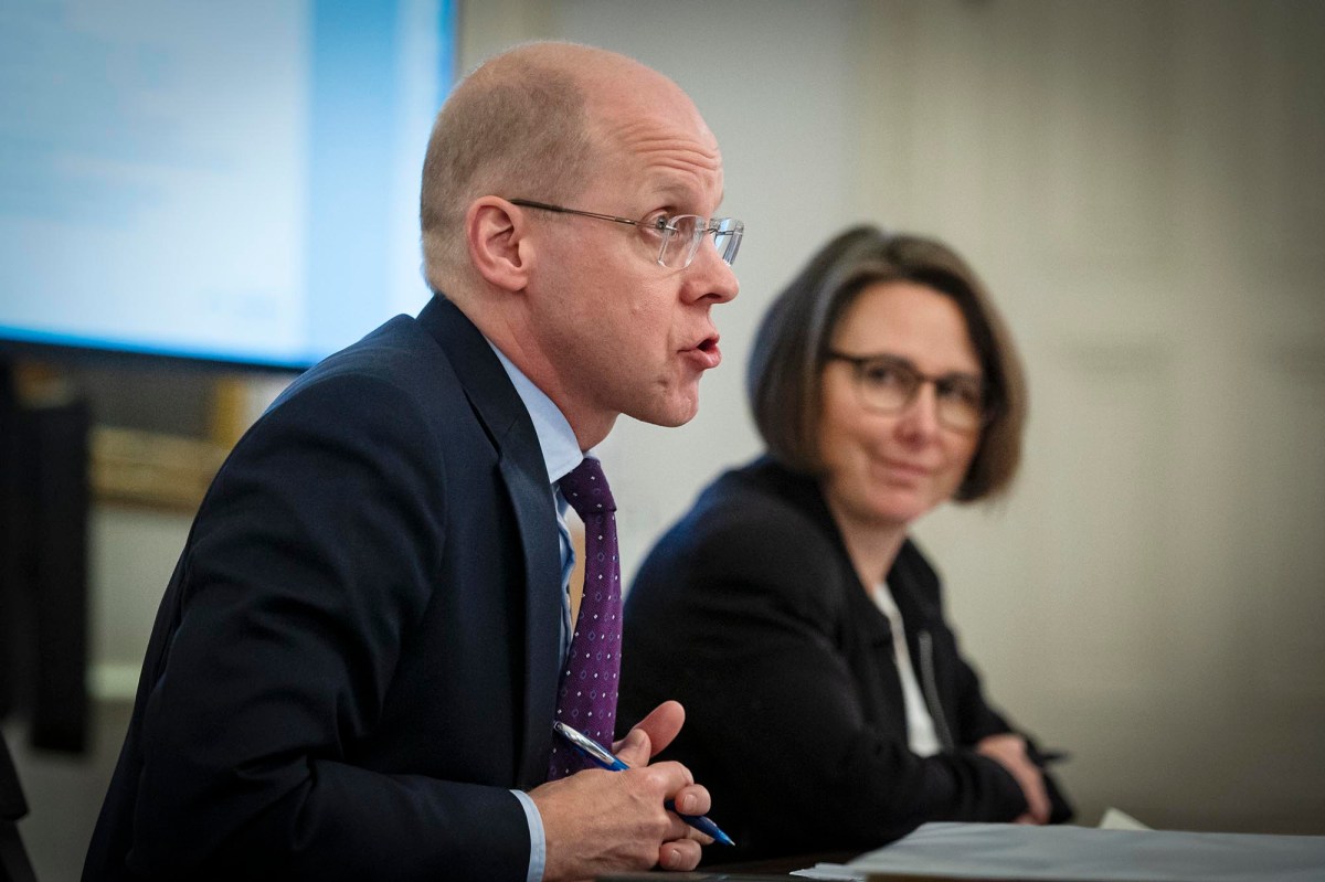 A man and woman sitting at a table in front of a screen.