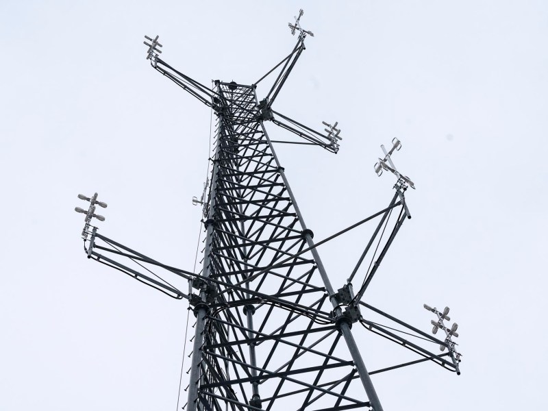A tall tower with many antennas against a cloudy sky.