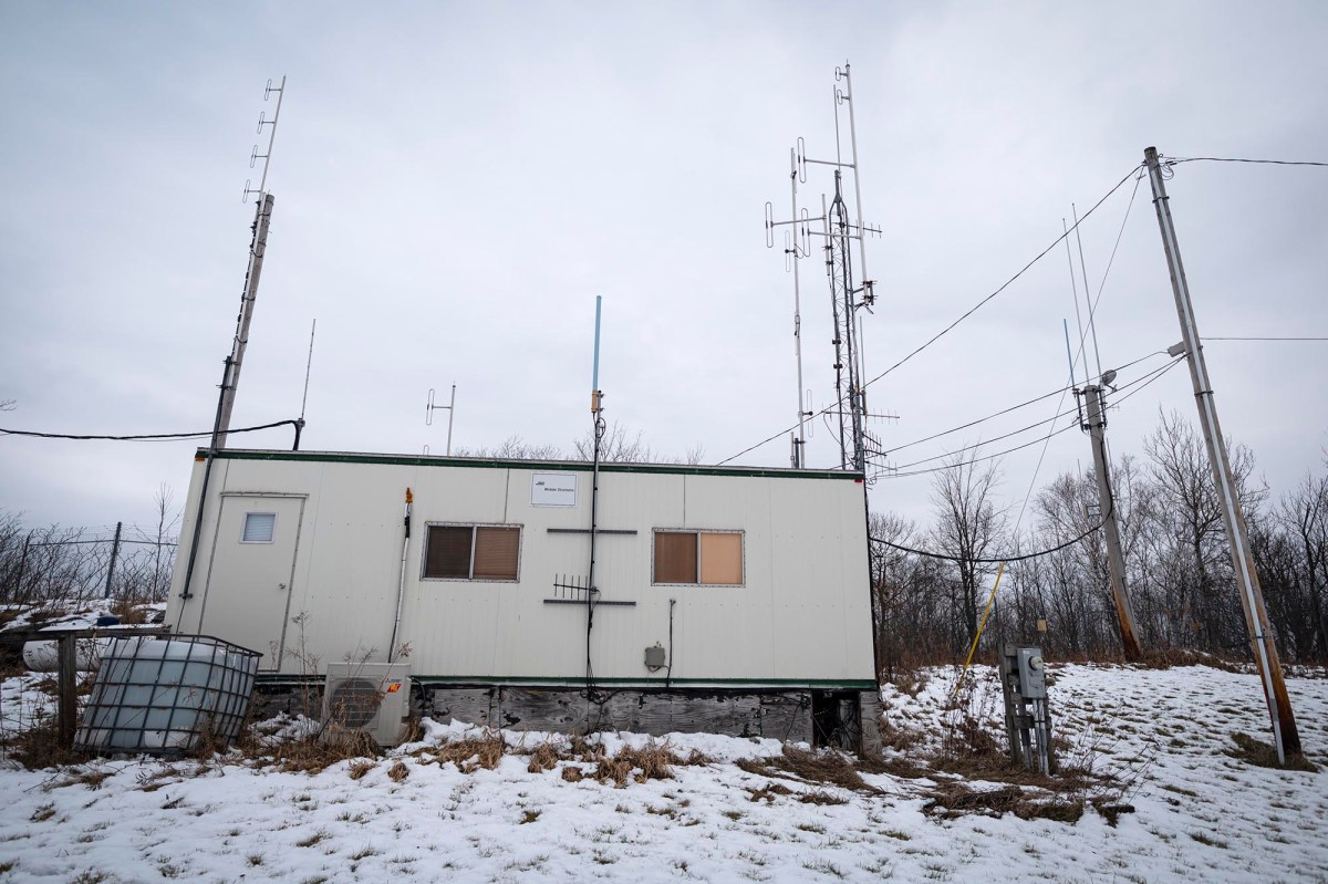 A small building with antennas in the snow.