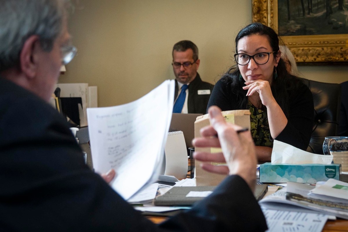 A group of people sitting at a table with papers in front of them.