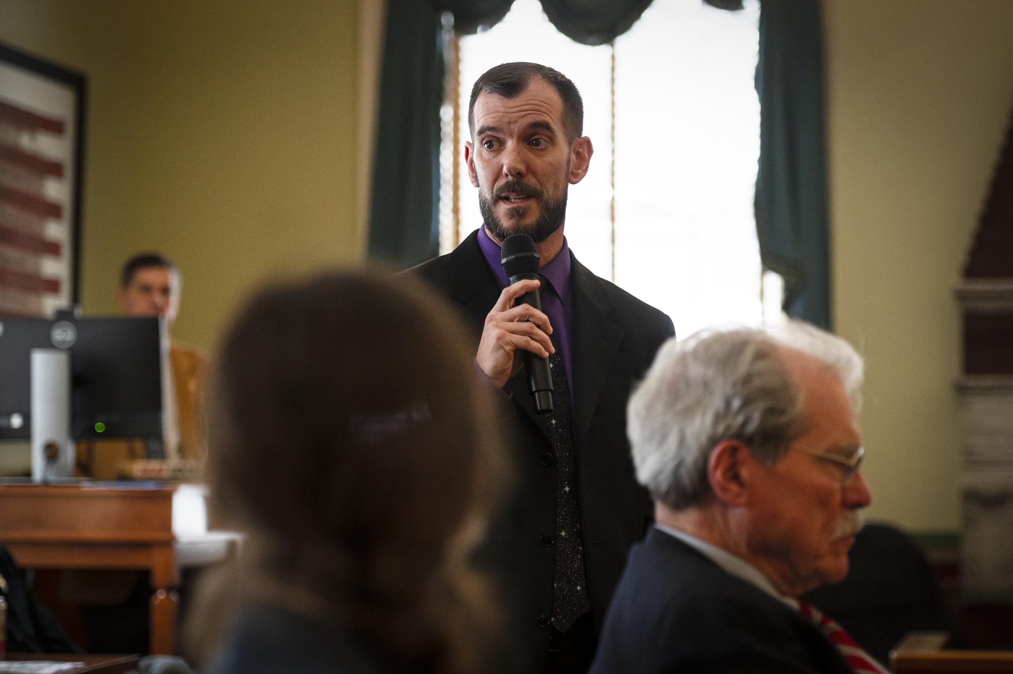 A man in a suit speaking into a microphone.