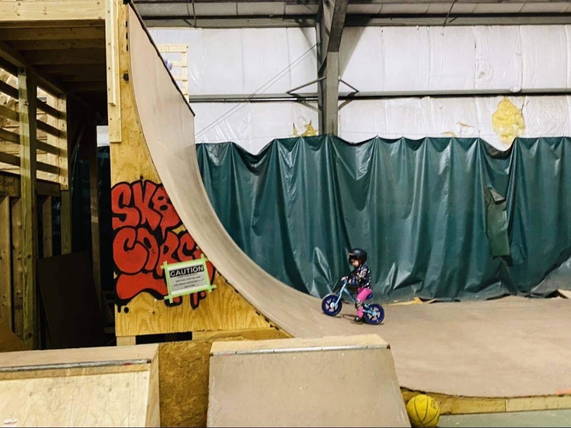 A child riding a skateboard in an indoor skate park.