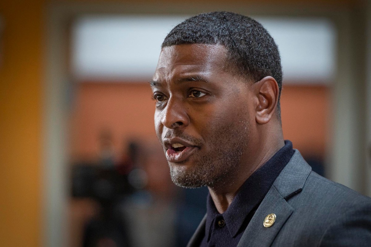 a black man in a suit talking to the camera.