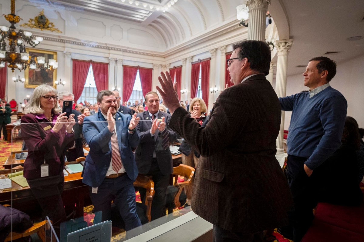 A group of people standing in a room and clapping.