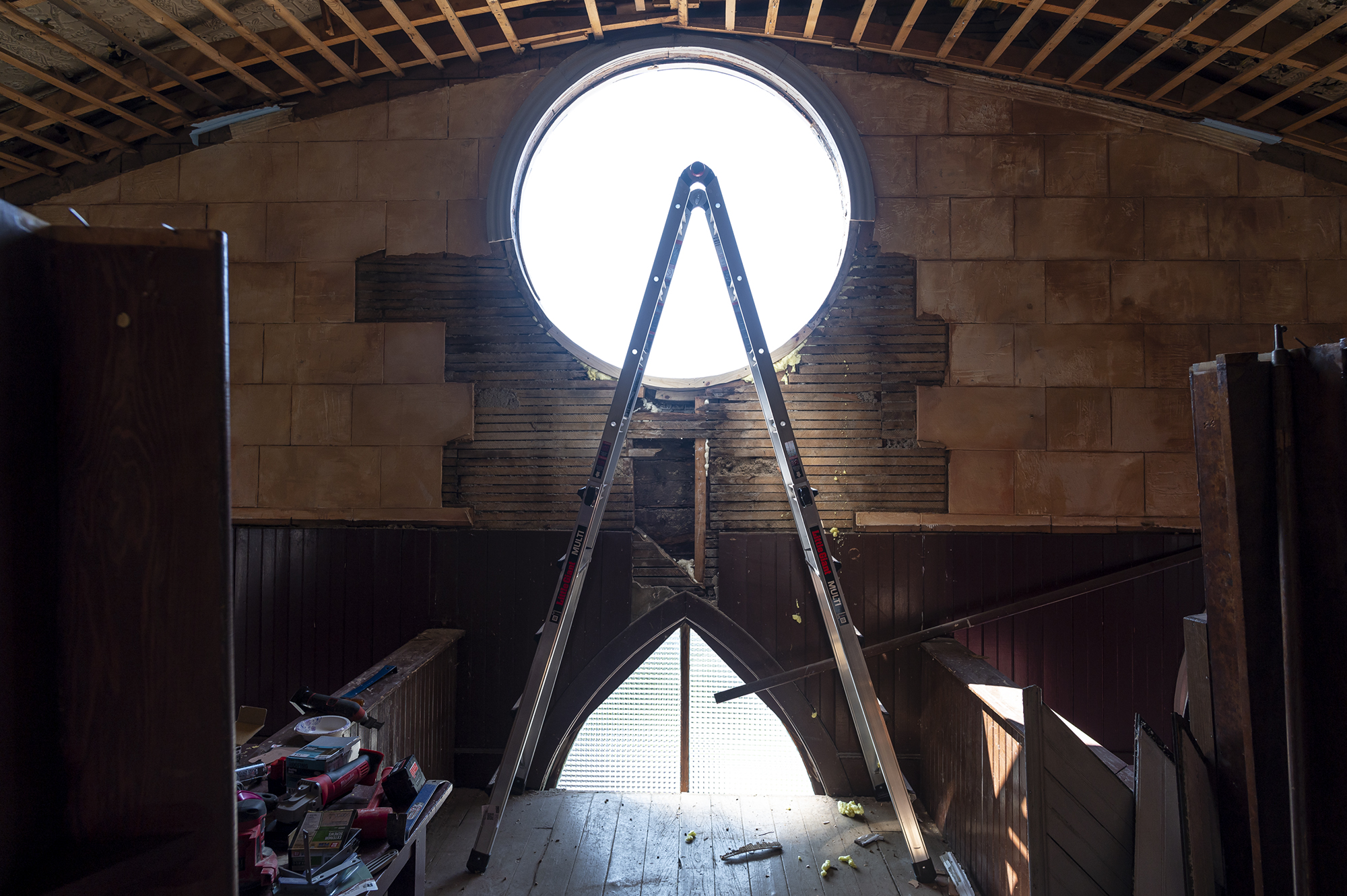 A ladder is in a room with a window.