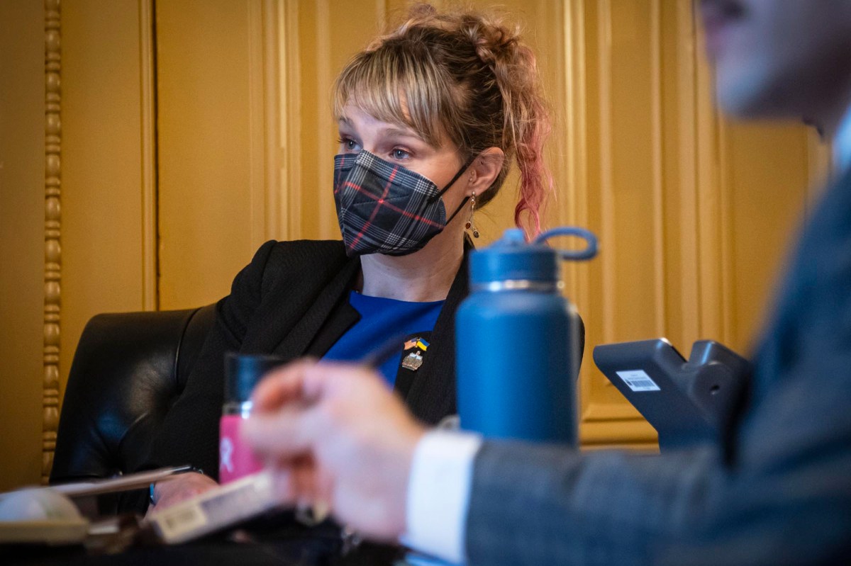 A woman wearing a face mask sits at a desk.