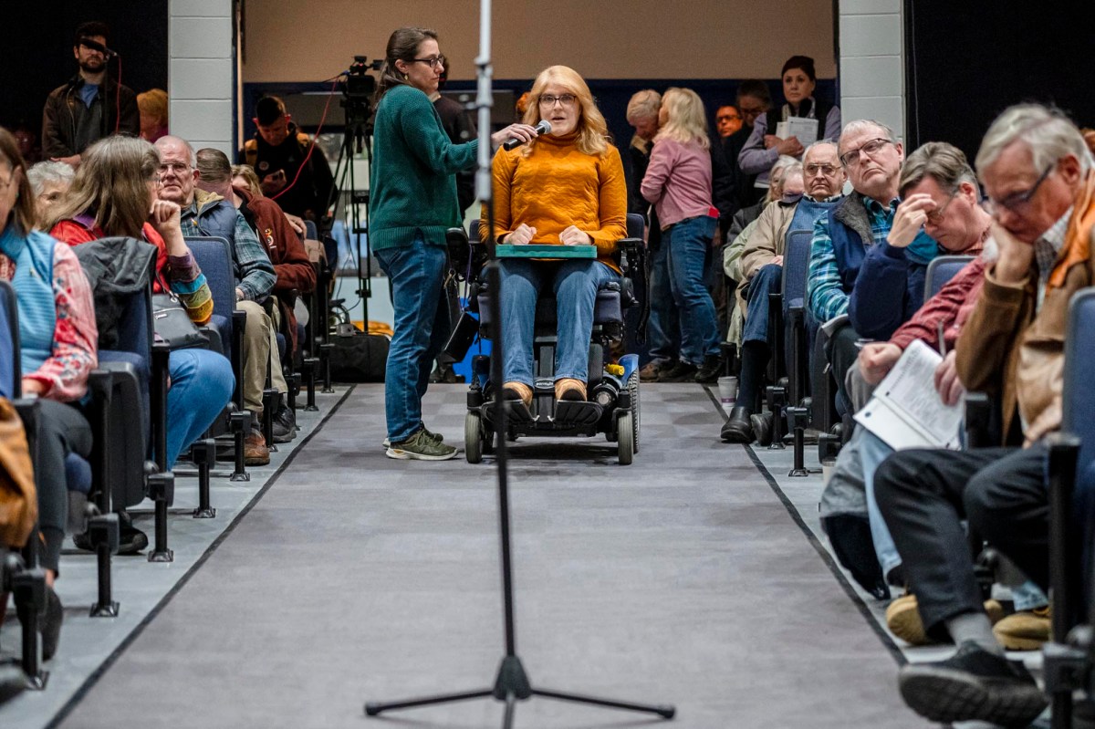 A woman in a wheelchair in front of a crowd of people.
