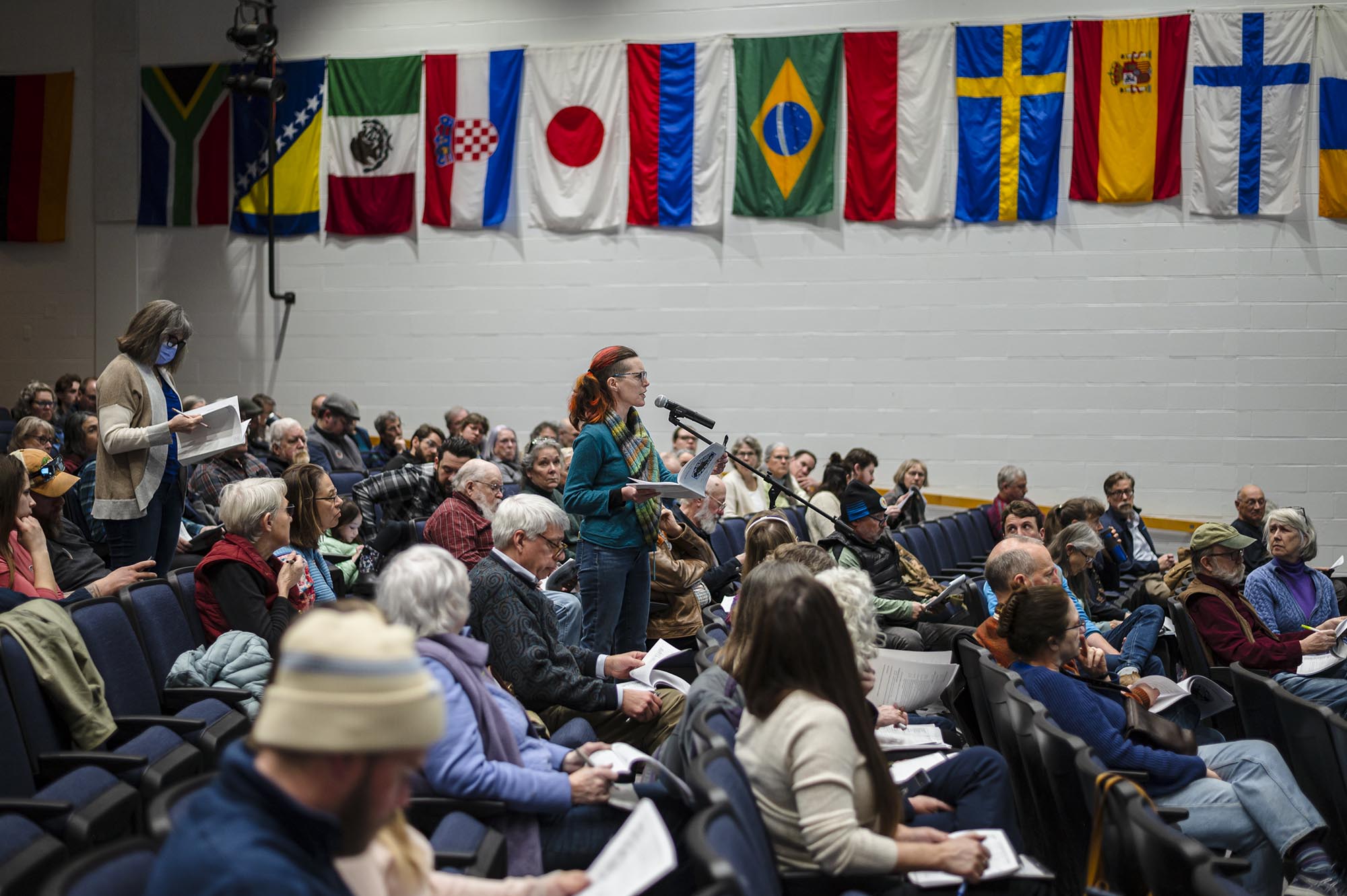 A group of people sitting in a room with flags.