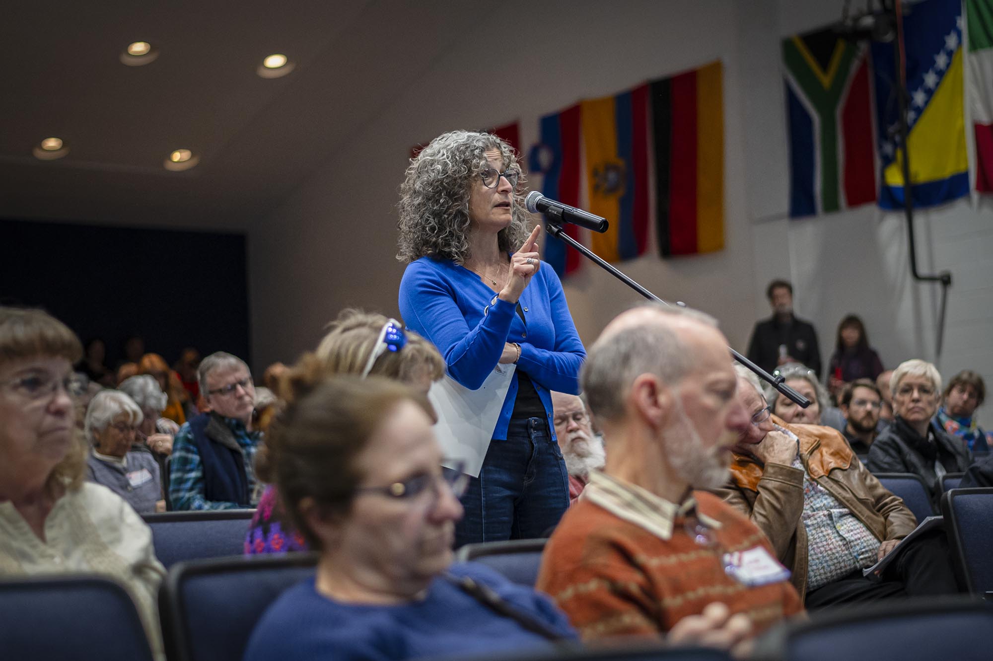 A woman speaking into a microphone in front of an audience.