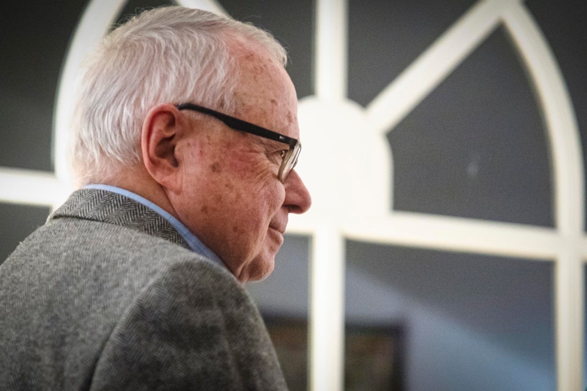 A man in glasses is standing in front of a window.