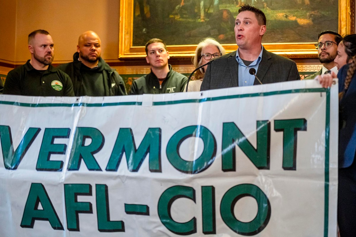 Man speaking at a vermont afl-cio event with attentive audience members in the background.