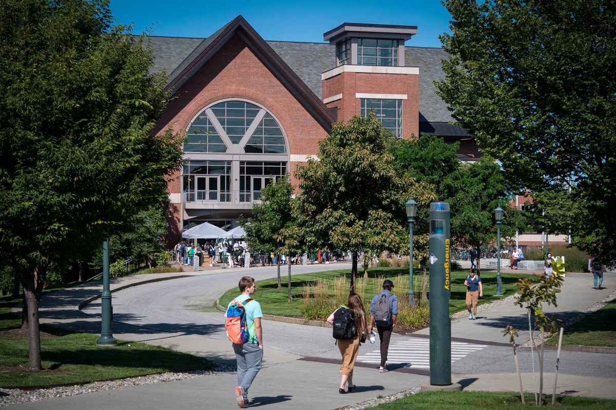 A group of people walking down a sidewalk in front of a building.