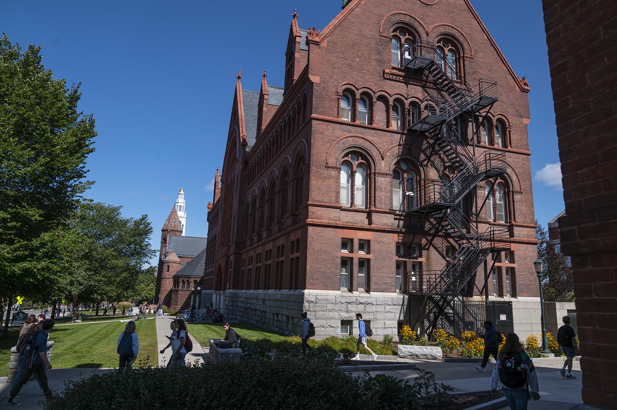 A large red brick building with people walking in front of it.