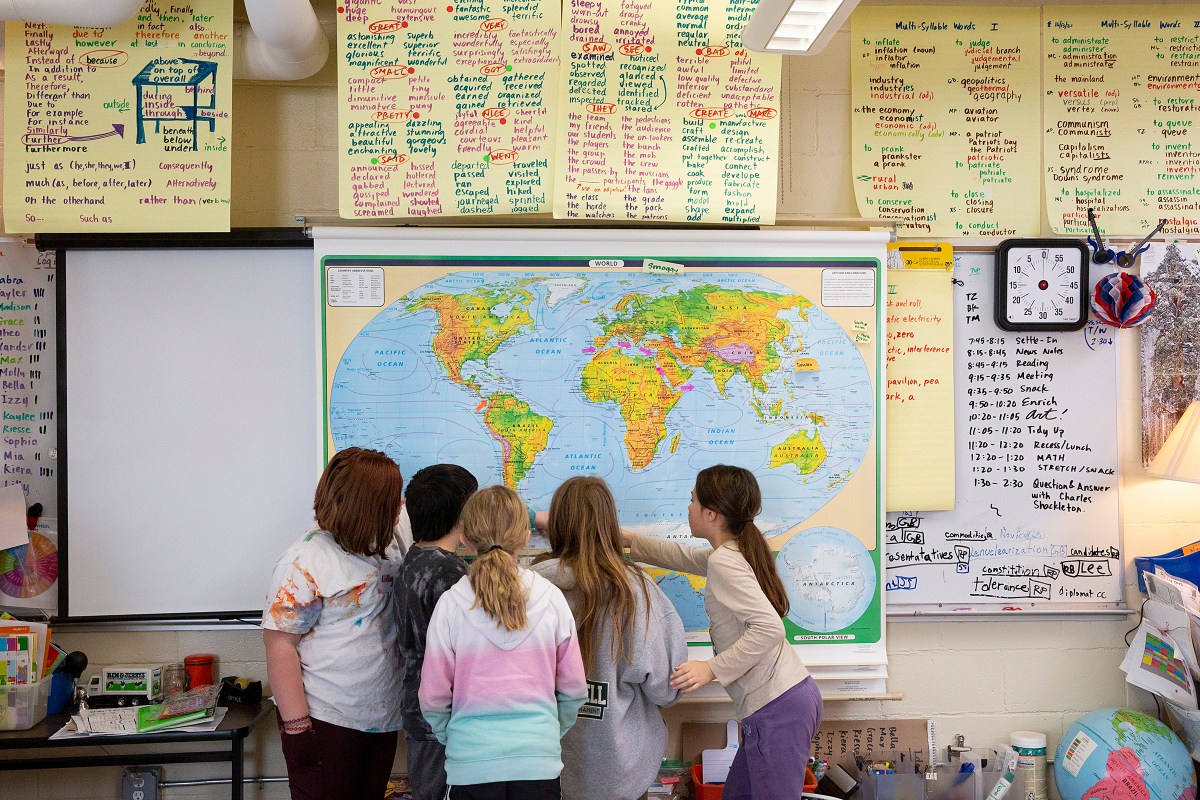 A group of children looking at a map in a classroom.