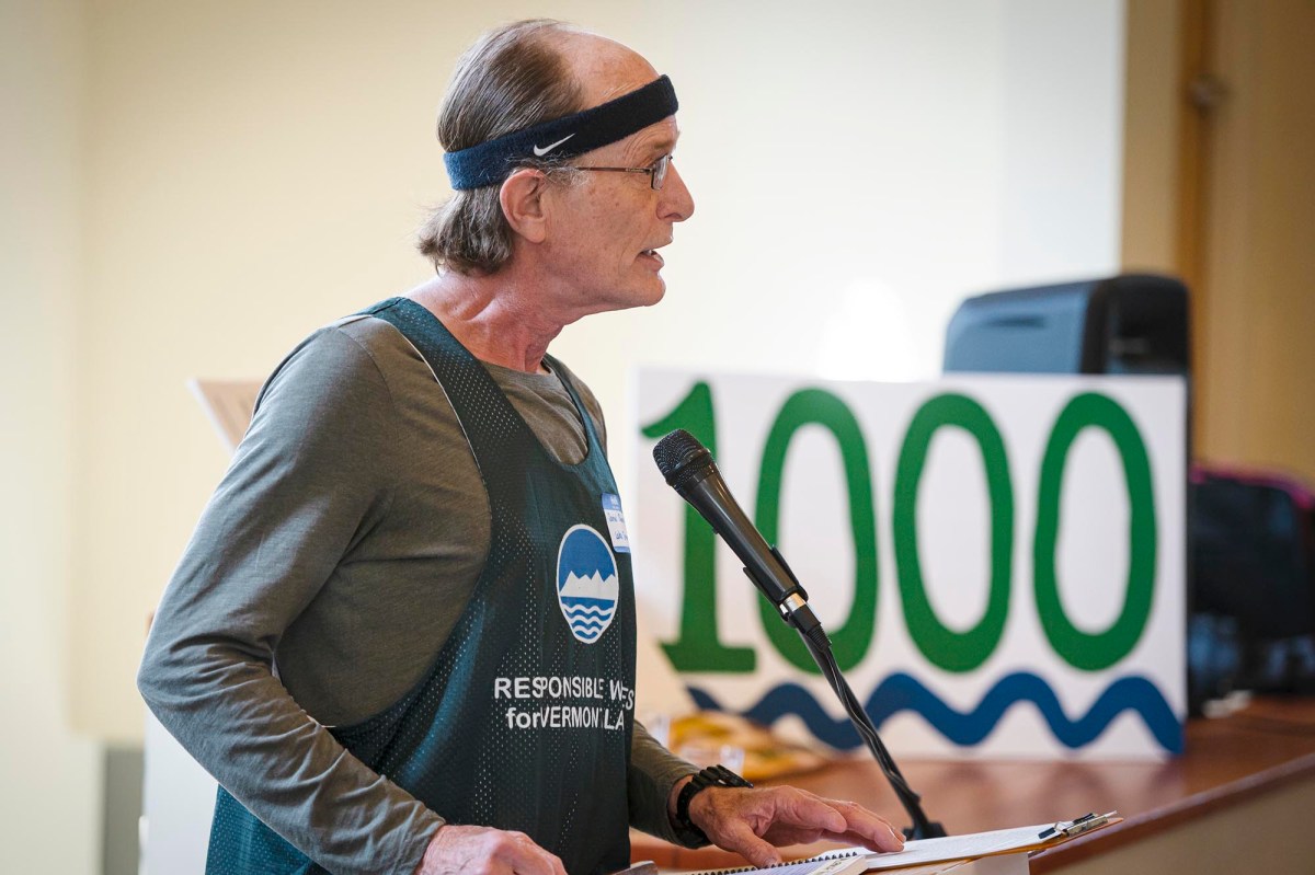A man in an apron speaking at a podium.