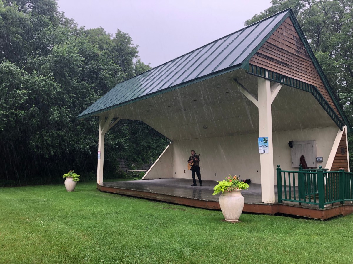 a person standing under a pavilion in the rain.