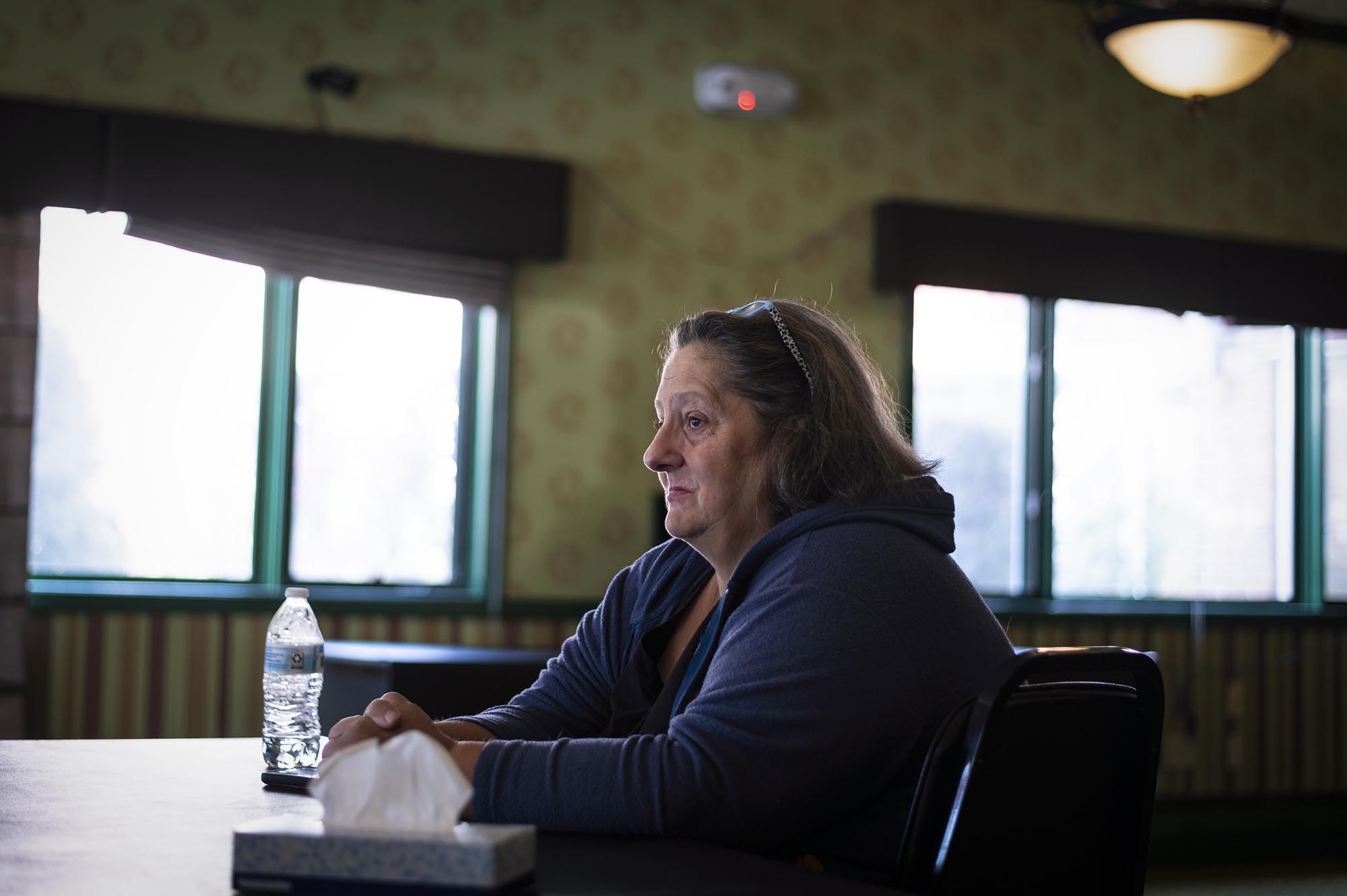 A woman sitting at a table with a tissue in front of her.