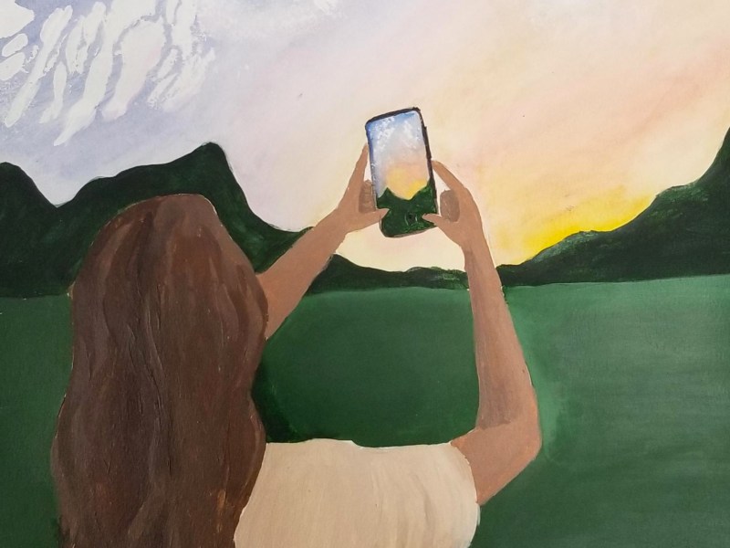 A painting of a woman with long, dark hair taking a photo of a sunset over a mountainous lake landscape with her smartphone.