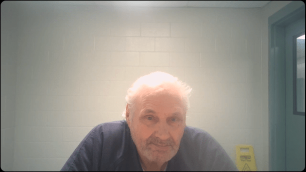 A man in a jail cell looking at the camera.