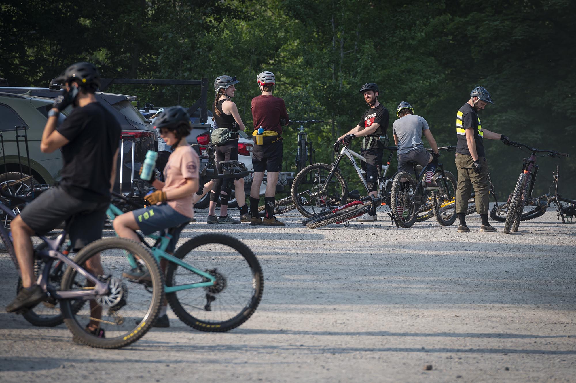 a group of mountain bikers standing in a parking lot.