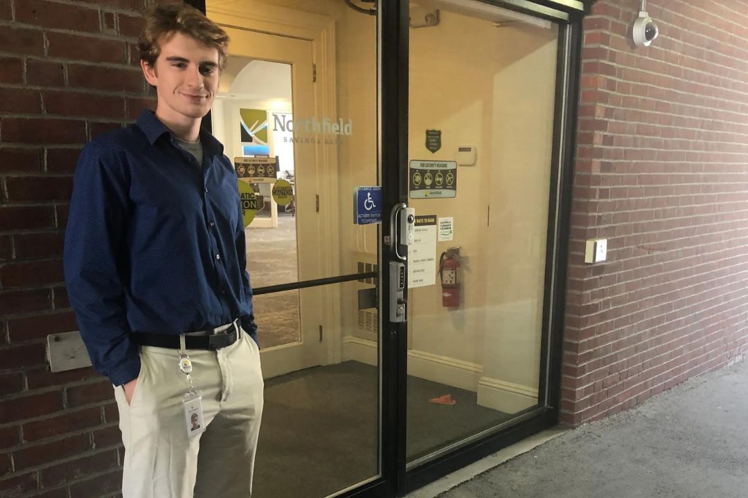 A man stands in front of a bank branch.