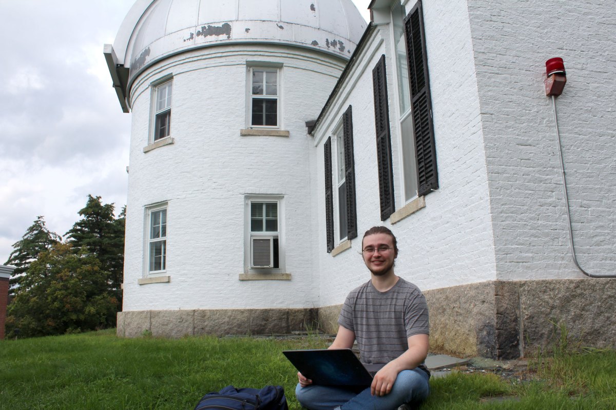 A man sitting in front of a building with a laptop.