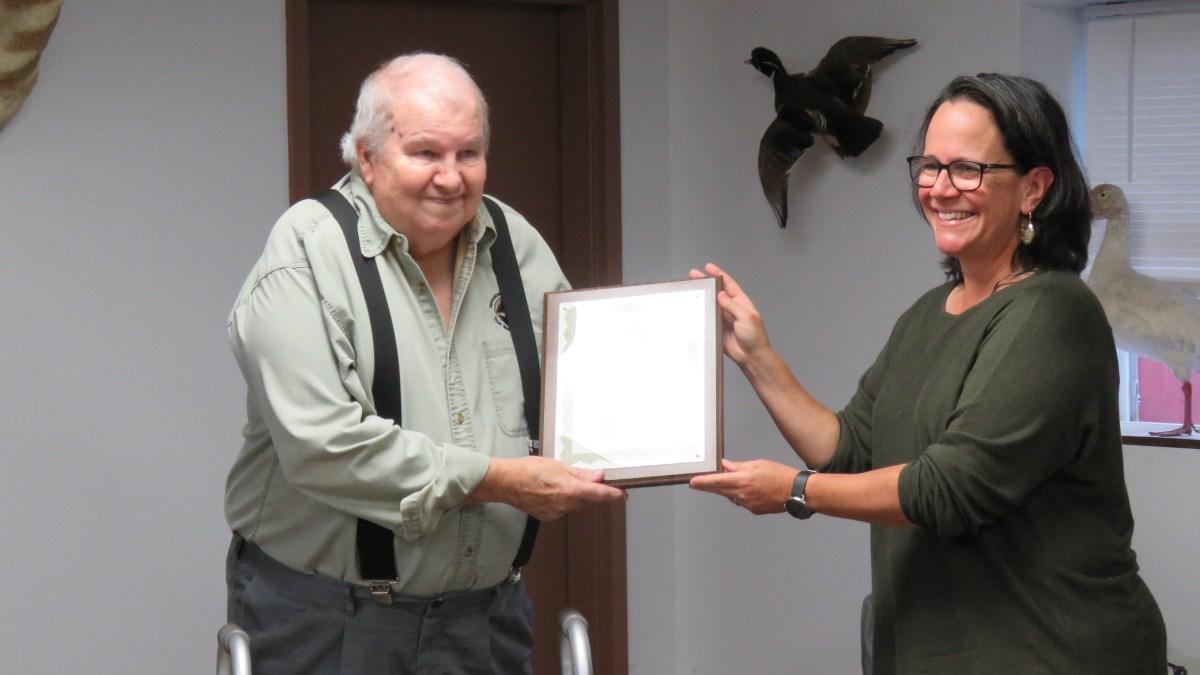 A man on the left receives an award from a woman on the right.