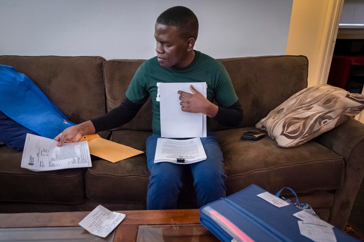 A man sitting on a couch with papers in front of him.