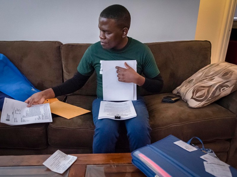 A man sitting on a couch with papers in front of him.