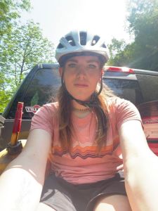 A woman in a pink shirt and bike helmet.