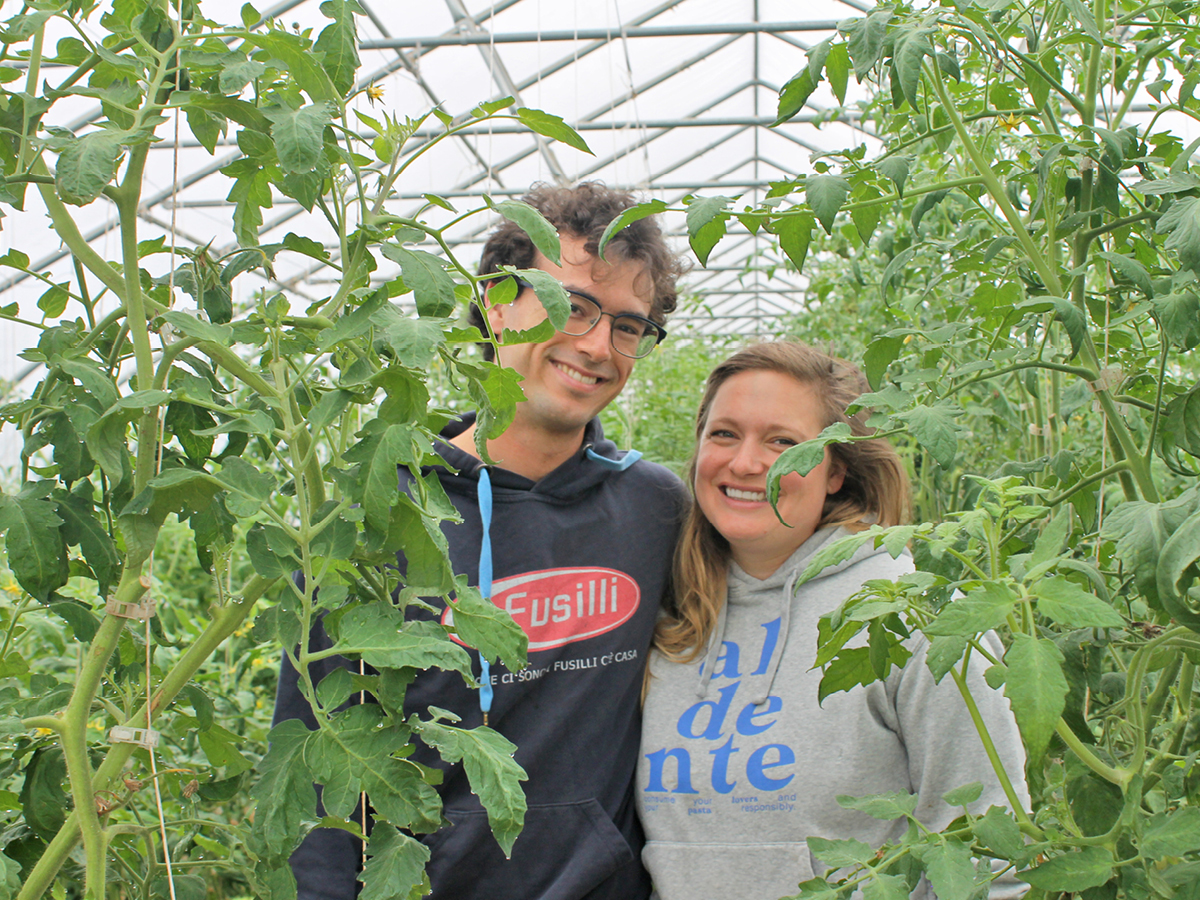 A man and a woman standing in a greenhouse.