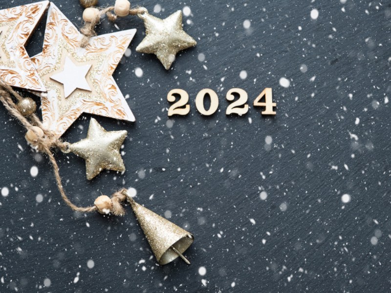 2024 on a snowy background with gold stars and bells.