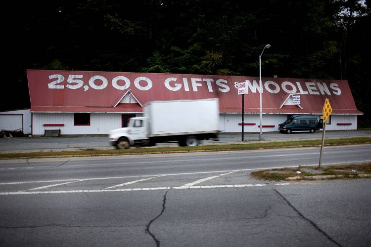 A truck driving past a building with a sign that says 25,000 gifts and noodles.