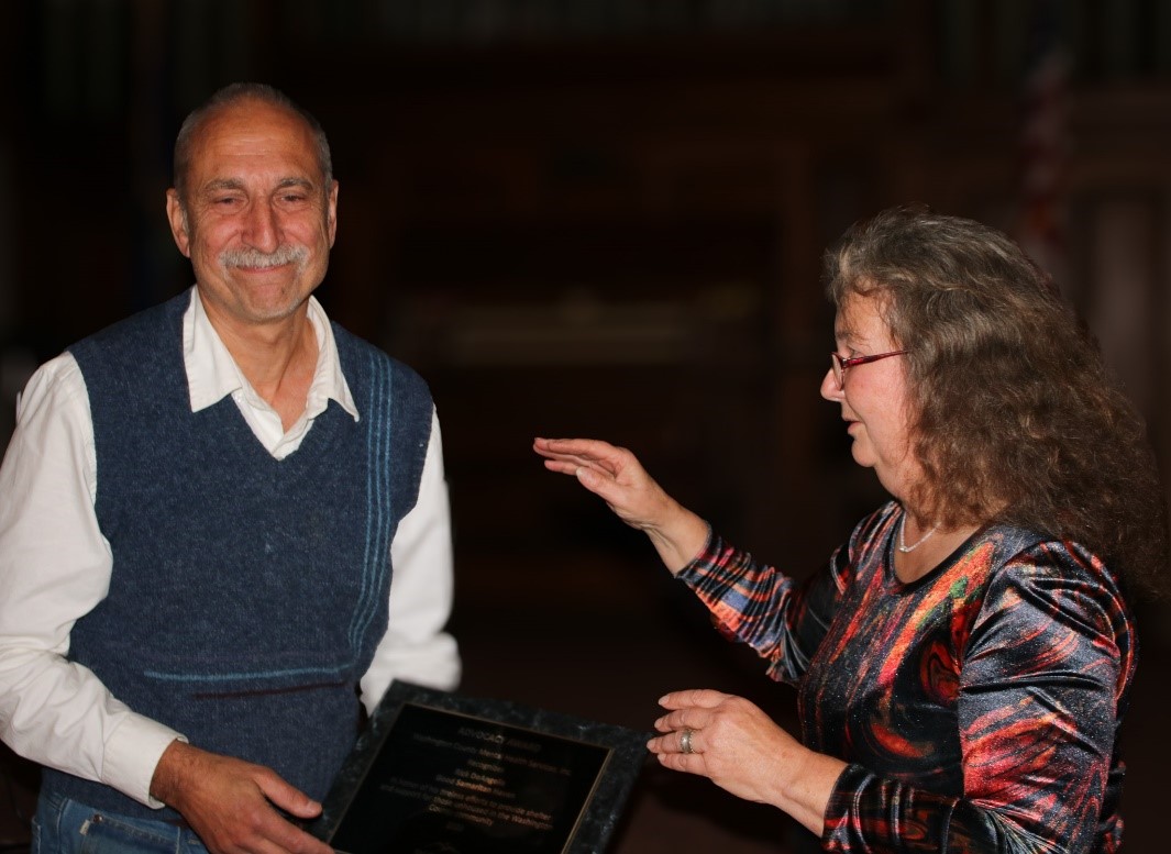 A man and woman standing next to each other holding a plaque.