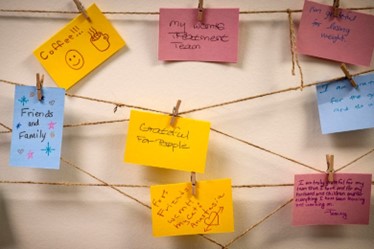 A group of post it notes hanging on a clothesline.