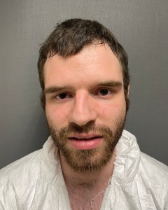 A man standing against a gray wall.