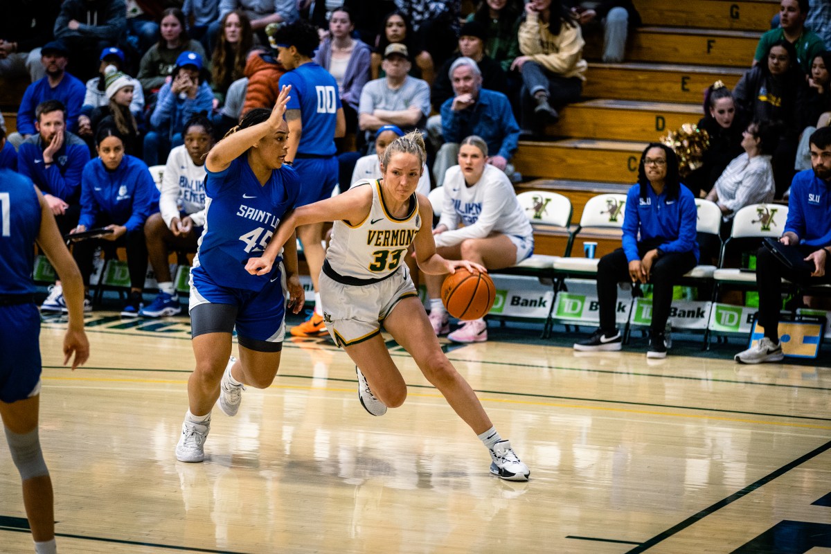 A basketball player dribbles the ball past a defender.
